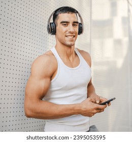 Portrait of young man outdoor use headphones and smart phone to play music or watch video podcast - Shutterstock ID 2395053595