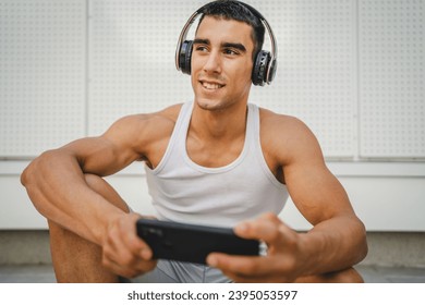 Portrait of young man outdoor use headphones and smart phone to play video games - Shutterstock ID 2395053597