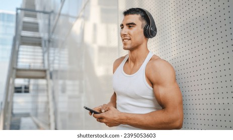 Portrait of young man outdoor use headphones and smart phone to play music or watch video podcast - Shutterstock ID 2395053603