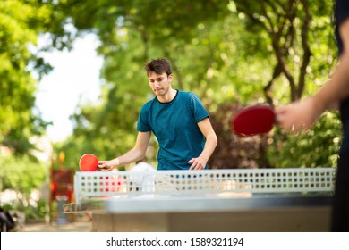 Portrait Of Young Man Playing Table Tennis In Park