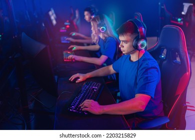 Portrait Young Man Pro Gamer With Headphones Playing In Online Video Game In Net Cafe, Neon Color Light, Soft Focus. Cybersport Team Concept.