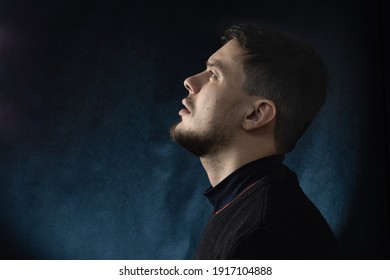 Portrait Of A Young Man In Profile, Looking Up Against A Dark Background.