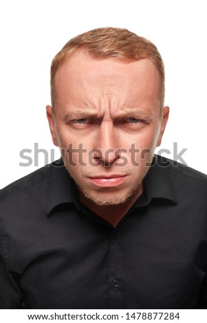Portrait of young man questionably mistrustfully looking with lowered eyebrows on white background.