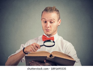 Porträt eines jungen Mannes, der ein interessantes Buch mit Lupe liest 