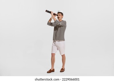 Portrait of young man, sailor in striped shirt looking in spyglass isolated on white background. Curious person. Concept of summer holidays, occupation, retro fashion, vintage style. Copy space for ad - Shutterstock ID 2229066001