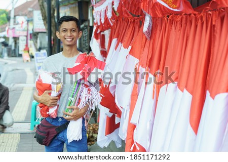 portrait of a young man selling the Indonesian national flag