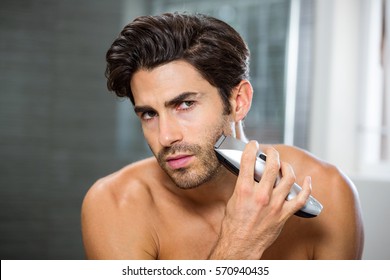 Portrait Of Young Man Shaving With Trimmer