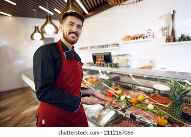 Portrait of a young man shopkeeper standing by meat stall in supermarket