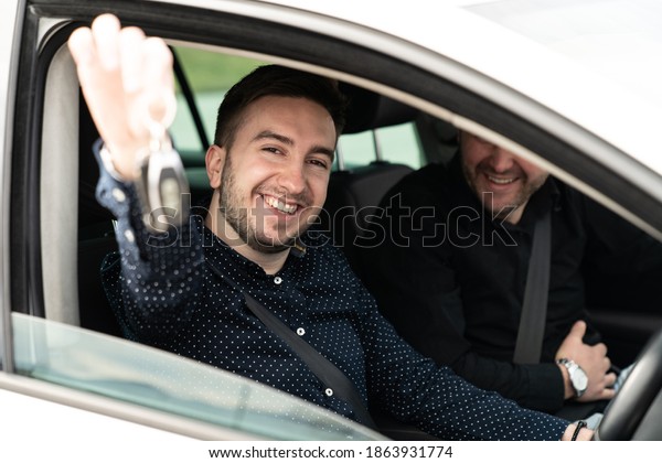 Portrait of a Young Man Showing a Car Key While\
Sitting in a Car