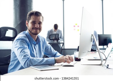 Portrait Of Young Man Sitting At His Desk In The Office