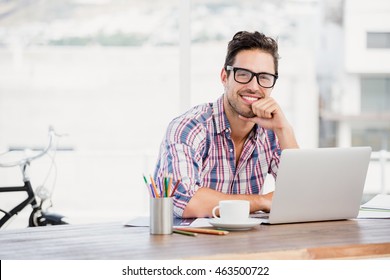 Portrait of young man sitting at his desk in the office