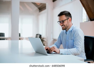 Portrait of young man sitting at his desk in the office - Shutterstock ID 648506098
