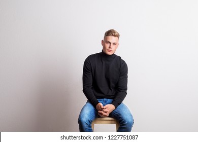 Portrait Of A Young Man Sitting On A Stool In A Studio. Copy Space.