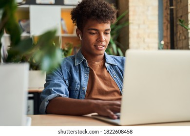 Portrait Of Young Man Sitting At The Table And Working On Laptop At Cafe. Freelancer Reading Important Document Or Contract