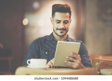 Portrait of young man smiling while using tablet at cafe - Powered by Shutterstock