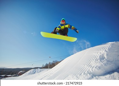 Portrait Of Young Man Snowboarding In Winter Against Blue Sky