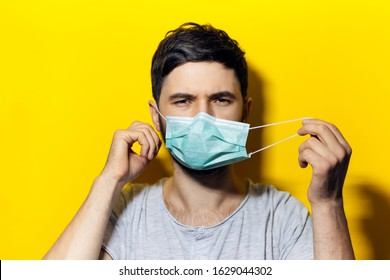 Portrait of young man, takes off the medical flu mask, on background of yellow color. - Powered by Shutterstock