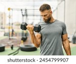 Portrait of a young man or trainer exercising in a gym, lifting weights, dumbbell equipment, healthy lifestyle and strength exercise at fitness club concepts