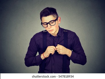 Portrait Young Man In Unpleasant Awkward Situation Playing Nervously With Hands Isolated On Gray Background. Negative Emotions