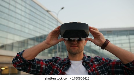 Portrait of a young man using a VR headset. Tapping the virtual screen. Camera moving around. Blurred background.