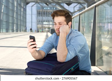 Portrait Of A Young Man Waiting At Airport With Bored Expression On Face