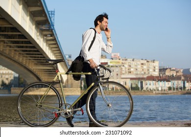 Portrait of a young man walking with bicycle and talking on cellphone - Powered by Shutterstock