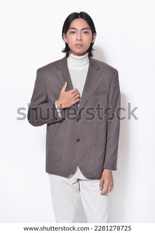 portrait of young man wearing brown suit, sweater with khaki pants posing on white background,