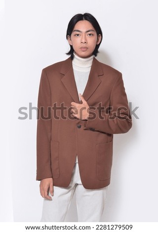 portrait of young man wearing brown suit, sweater posing on white background,