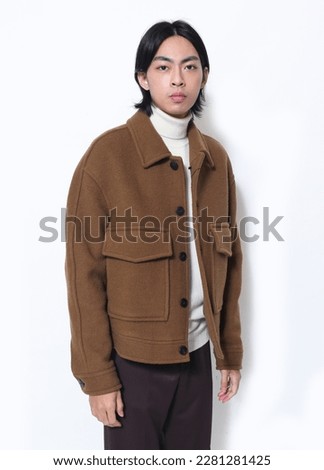 portrait of young man wearing brown coat posing on white background,