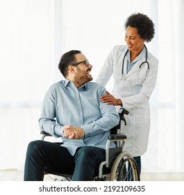 Portrait Of A Young Man In Wheelchair And His Doctor At Home Or In Hospital, Man With Chronic Health Condition And Paraplegia