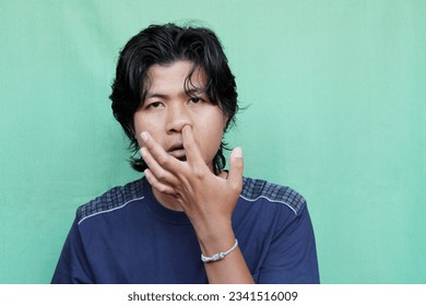 portrait of a young man wiping his nose with a finger against a green screen background - Powered by Shutterstock