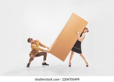 Portrait Of Young Man And Woman Carrying Giant Cardboard Boxes. New Apartment Furniture Shopping. Moving Into New Flat. Concept Of Retro Fashion, Style, Youth Culture, Emotions, Ad