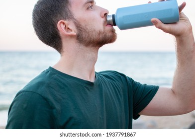 Portrait Of A Young And Masculine Man Drinking Water Outside After A Train At A Gym. Relax After Running At The Beach.