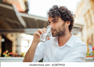 portrait of a young and masculine man drinking a water outside - Powered by Shutterstock