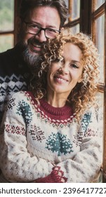 Portrait of young mature couple smiling and standing for a picture, Man and woman wearing warm sweater with christmas decorations and color. People in love in a wooden chalet or home in leisure time - Shutterstock ID 2396417727