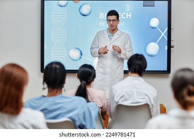 Portrait of young medical professional giving lecture or presentation standing by screen at seminar and speaking to audience - Powered by Shutterstock