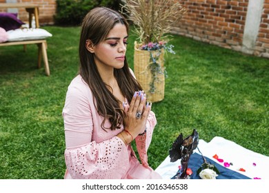 Portrait of young mexican woman meditating with hands in prayer position in holistic therapy