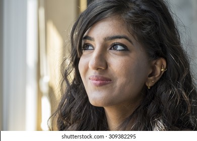 Portrait of a  young middle eastern woman smiling, in window light
