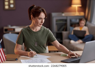 Portrait of young military woman using laptop and working at desk in office - Powered by Shutterstock