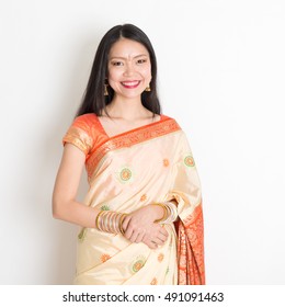 Portrait Of Young Mixed Race Indian Chinese Woman With Traditional Sari Dress Smiling, Standing On Plain Background.