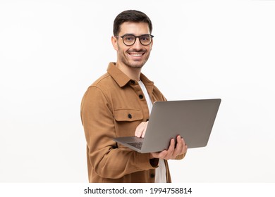 Portrait Of Young Modern Business Man Standing In Casual Brown Shirt, Holding Laptop And Looking At Camera With Happy Smile, Isolated On Gray