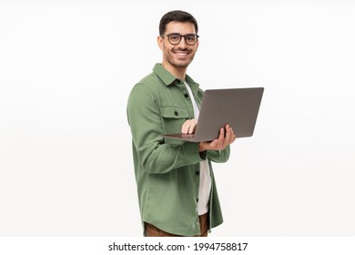 Portrait of young modern businessman standing holding laptop and looking at camera with happy smile, isolated on gray - Shutterstock ID 1994758817
