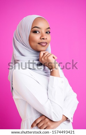 portrait of young modern muslim afro beauty wearing traditional islamic clothes on plastic pink background