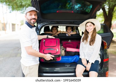 Portrait Of A Young Mom And Dad Packing Their Luggage And Things In The Car To Travel To The Mountains With Their Children For A Family Vacation