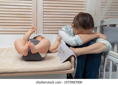Portrait of a young mother in a depressed state and sitting next to her baby indoors