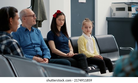 Portrait Of Young Mother And Little Girl Being Seated In Waiting Room, Having Appointment With Physician At Medical Clinic. Woman With Child In Hospital Reception Lobby, Waiting In Row.