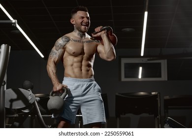 Portrait of young muscular man training shirtless in gym indoors. Hand exercises with kettlebell. Relief body shape. Concept of health, sportive lifestyle, fitness, body care, diet, strength - Shutterstock ID 2250559061
