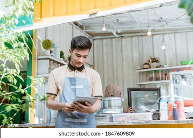 portrait of young muslim men selling food and drinks at his small shop made of truck container box - Powered by Shutterstock