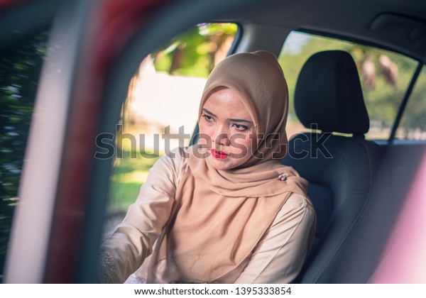 portrait of young Muslim woman in\
hijab sitting on car seat, car interior, female drivers\
concept.