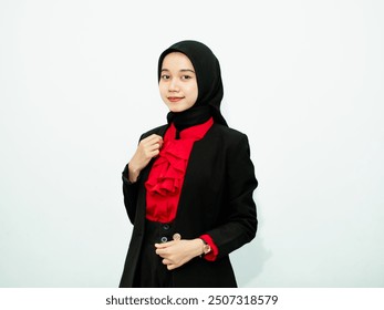 Portrait of a young Muslim woman wearing a black hijab and formal attire, confidently adjusting her blazer while smiling, isolated on a plain white background. Showcasing professionalism. - Powered by Shutterstock